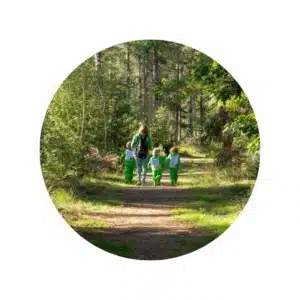 Kinderen en pedagogisch medewerker wandelen in het bos peuteropvang locatie Galder